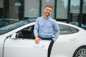 handsome young businessman standing near his car outdoors. photo