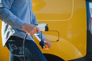 Smiling man unplugging the charger from the car photo