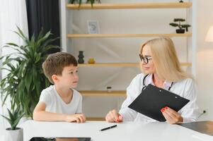 cuidado de la salud para niños pequeño chico hablando a médico durante visitar a hospital. foto