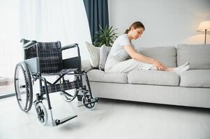woman trying to sit down in wheelchair from couch photo