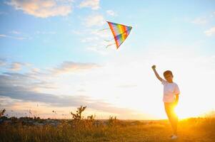 Boy is running with a kite during the day in the field photo