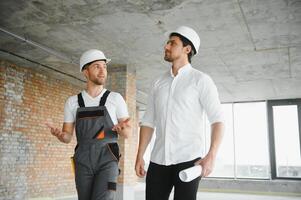 Engineer and worker checking project at building site background, construction site at sunset in evening time photo