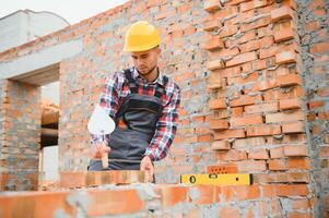 instalación de pared de ladrillo. trabajador de la construcción en uniforme y equipo de seguridad tiene trabajo en la construcción foto