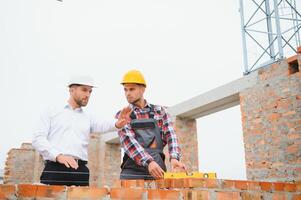 Construction engineers supervising progress of construction project stand on new concrete floor top roof and crane background. photo