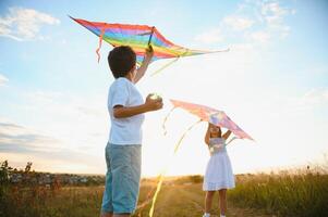 Happy children launch a kite in the field at sunset. Little boy and girl on summer vacation. photo