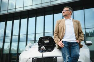 hombre cargos un eléctrico coche a el cargando estación foto