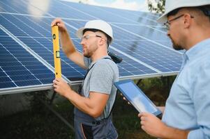 Male engineer in protective helmet installing solar photovoltaic panel system. Alternative energy ecological concept. photo