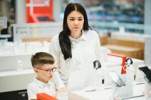 mujer con hijo en Tienda comprando nuevo teléfono. foto