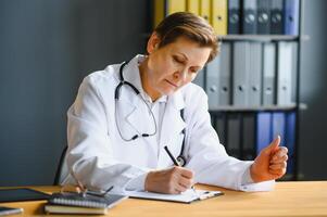 Portrait of mature female doctor in white coat at workplace photo