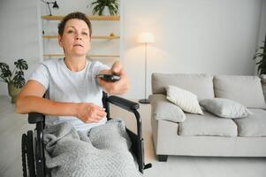 woman in wheelchair uses a tv remote control. photo