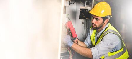 eléctrico ingeniero trabajo ensayador medición voltaje y Actual de poder eléctrico línea en eléctrico gabinete controlar para industrial producción. panorama imagen utilizar para cubrir diseño. foto