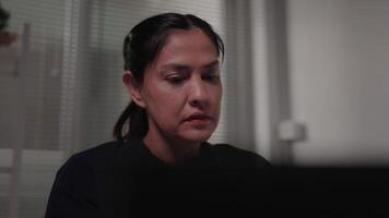 cansado mujer de negocios trabajos a computadora desde hogar a noche. hembra empresario es decepcionado, estresado, mecanografía a computadora portátil, leyendo malo Noticias en social medios de comunicación. video