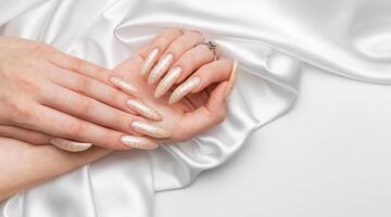 Female Hands on a white silk background with beautiful pearl manicure photo