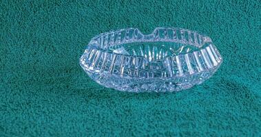Empty crystal ashtray on green background. The ashtray was made in the mid-20th century. photo