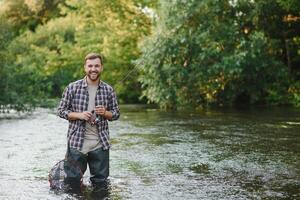 Fisherman catches a trout on the river in summer photo