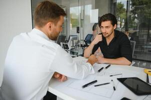 Two engineering working together and using digital tablet looking blueprint and analysis with architectural plan on desk photo