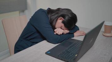 cansado mujer acostado en un de madera mesa en el oficina trabajo desde tu vivo habitación a hogar. socialmente distancia. video