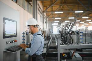 Operator wearing safety hat behind control panel on a factory photo