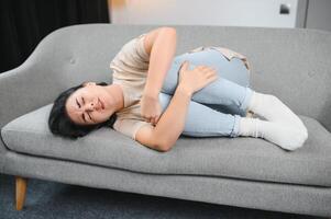 Menstruation, period cycle day of monthly, young woman, female hand in stomachache, suffer from PMS premenstrual, belly or abdomen pain on bed at home. Health problem Inflammation in body. photo