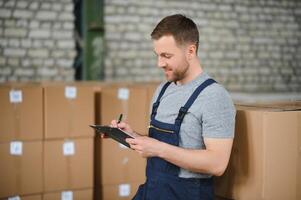 Portrait of happy male worker in warehouse standing between shelves. photo