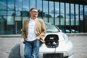 hombre cargos un eléctrico coche a el cargando estación foto