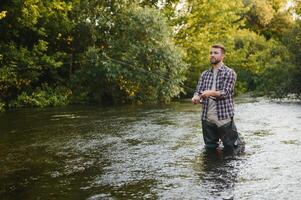 Fisherman catches a trout on the river in summer photo