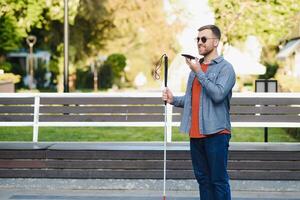 Young blinded man using phone and sending voice message photo