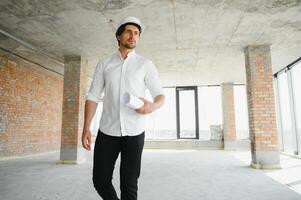 Portrait of man architect at building site. Confident construction manager wearing hardhat. Successful mature civil engineer at construction site with copy space. photo