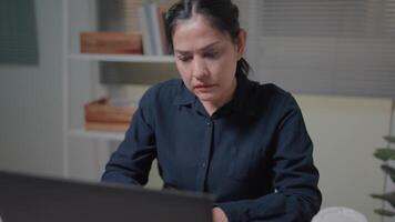 un mujer se sienta en frente de un computadora y siente estresado cuando ella hipocresía entregar el trabajo a el cliente en tiempo. video