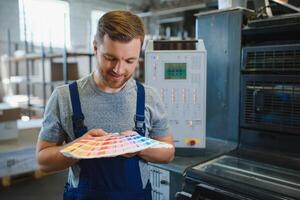 Funny portrait of typographer standing with color swatches at the printing manufacturing photo