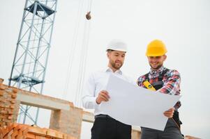 engineer architect with hard hat and safety vest working together in team on major construction site photo