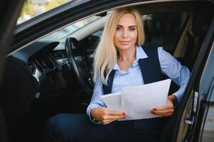 Fashion business woman with financial papers by her car photo