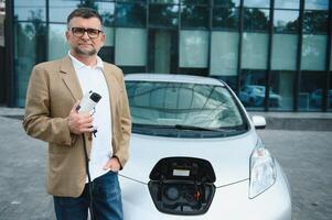 hombre cargos un eléctrico coche a el cargando estación foto