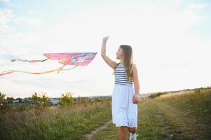 happy child girl with a kite running on meadow in summer in nature photo