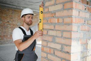 Man builder working in construction site. Male repairer in overall and helmet. photo