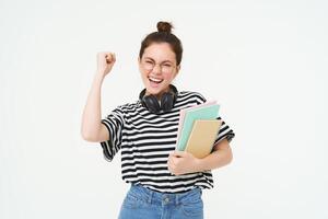 entusiasta joven mujer en anteojos, profesor celebrando, levantamiento mano arriba y aplausos, triunfando con alegre sonrisa, blanco antecedentes foto