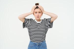 Portrait of woman in trouble, holding hands on head and panicking, looking worried, isolated over white background photo