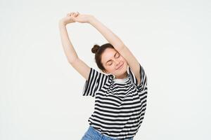 Portrait of happy young woman, stretching arms with pleased smile after good nap, standing over white background photo