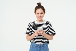 tecnología y personas concepto. joven mujer con móvil teléfono, sonriente, utilizando teléfono inteligente aplicación, social medios de comunicación solicitud, aislado terminado blanco antecedentes foto