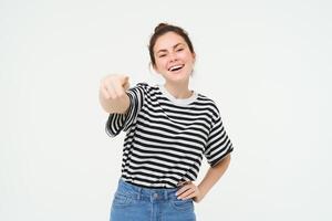 Image of stylish young woman, pointing finger at camera, inviting you, standing over white background photo