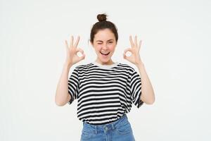 Excellent choice. Smiling stylish young woman, showing okay, ok gesture, zero sign, standing over white background photo
