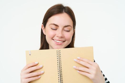 retrato de joven mujer hace notas en su planificador, escribe en diario, cheques su calendario en computadora portátil, participación organizador en manos, soportes terminado blanco antecedentes foto