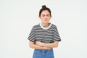 Portrait of woman grimacing from painful menstrual cramps, touches her belly, discomfort or stomach ache, stands over white background photo