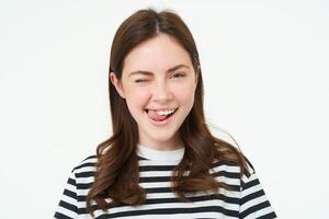 Portrait of happy, beautiful young woman, smiles and winks at you, stands over white background photo