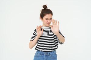 Image of woman refusing something, raising hands in defensive gesture, protecting herself, rejecting offer, declining, standing over white background photo