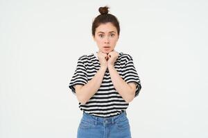 Portrait of young compassionate woman, looking with sympaty, gasping at camera, raising eyebrows, standing over white background photo