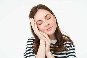 cerca arriba retrato de licitación, sonriente joven mujer, cierra su ojos y toques su palmera, dormido en su mano, aislado en blanco antecedentes foto