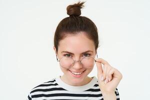 cerca arriba retrato de sonriente, hermosa joven mujer, estudiante en anteojos, mirando a cámara con confianza y reír, blanco antecedentes foto