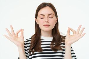 Everything under control. Young woman meditating, standing in zen, yoga pose, keeps calm, posing with closed eyes, breathing with relaxed mindful expression photo
