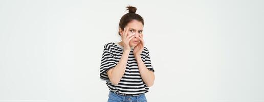 Image of woman looking scared, apalled by something shocking, standing over white background photo